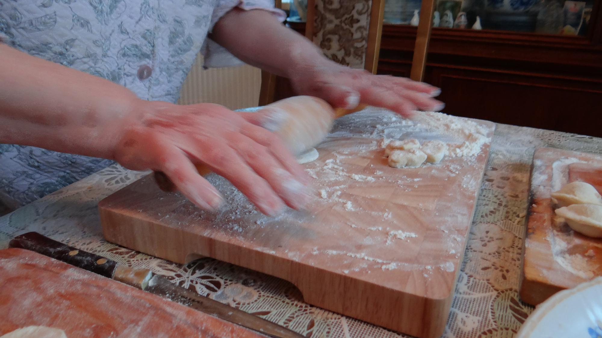 Close-up of hands kneading dough on wooden board